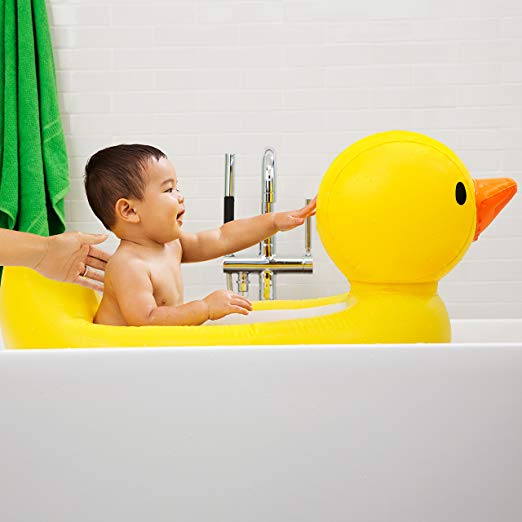 Baby plays in rubber duckie inflatable bathtub.