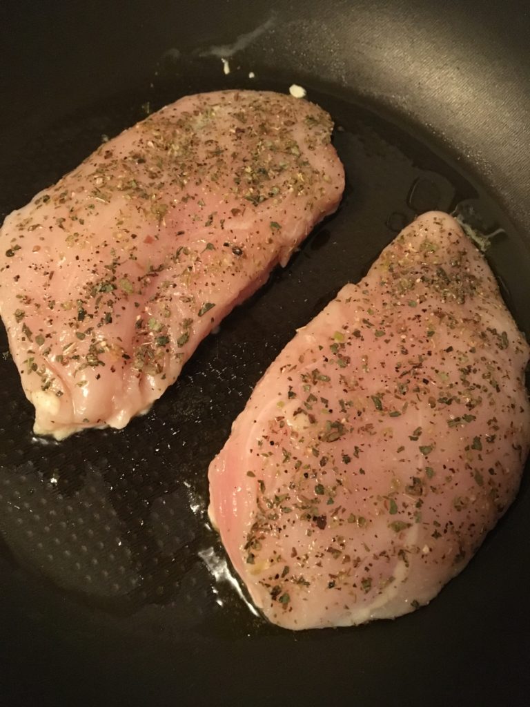 Raw chicken with seasonings on top.