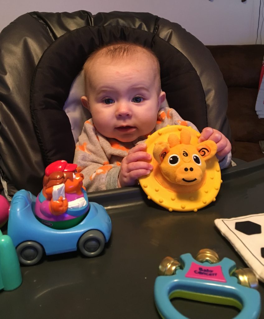 Baby plays with toys in high chair.