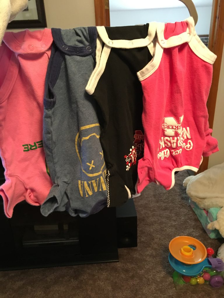 Several baby onesies hanging on hanger.