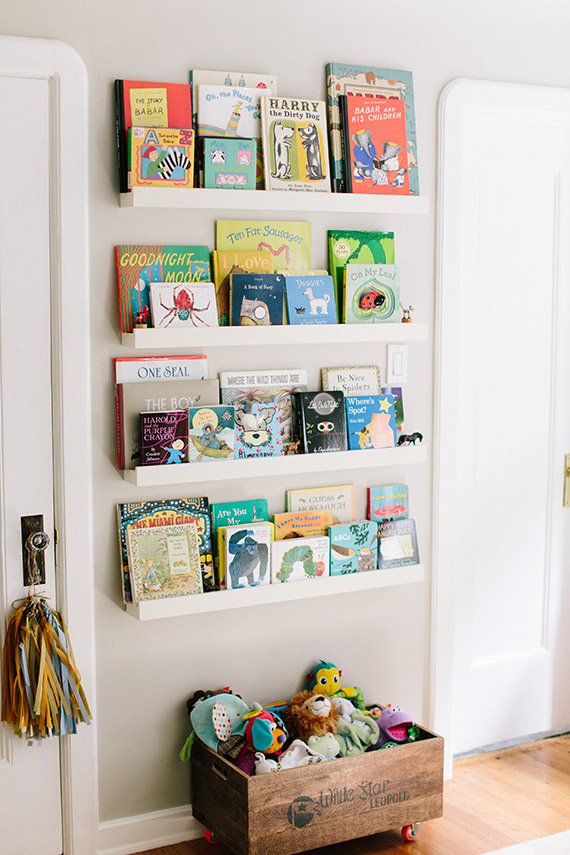 White, floating shelves filled with children\'s books.