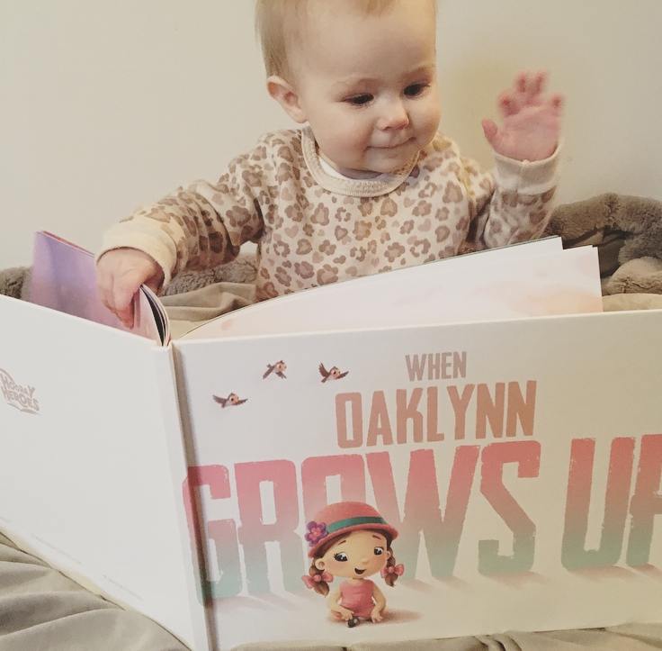 Baby girl reads personalized children's book.