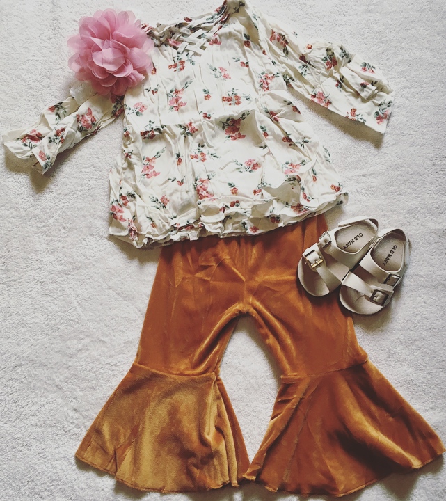 White top with pink ang green flowers next to velvety copper pants for little girl.