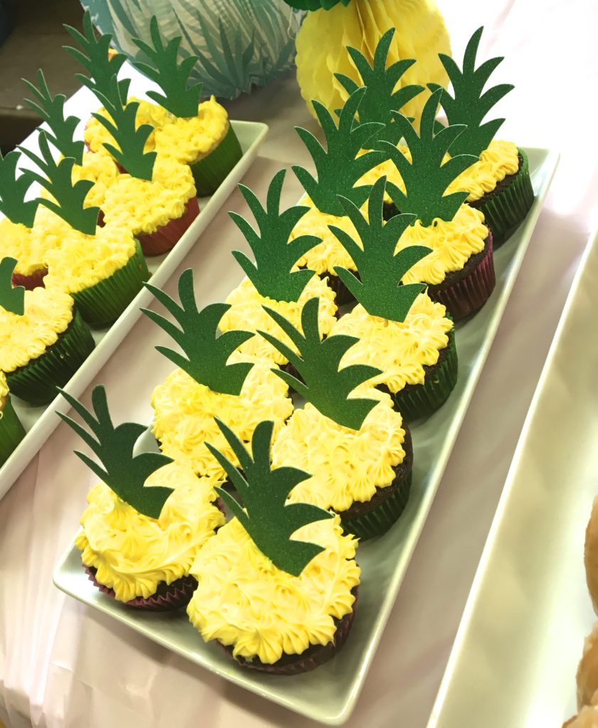 Yellow cupcakes topped with faux pineapple leaves.